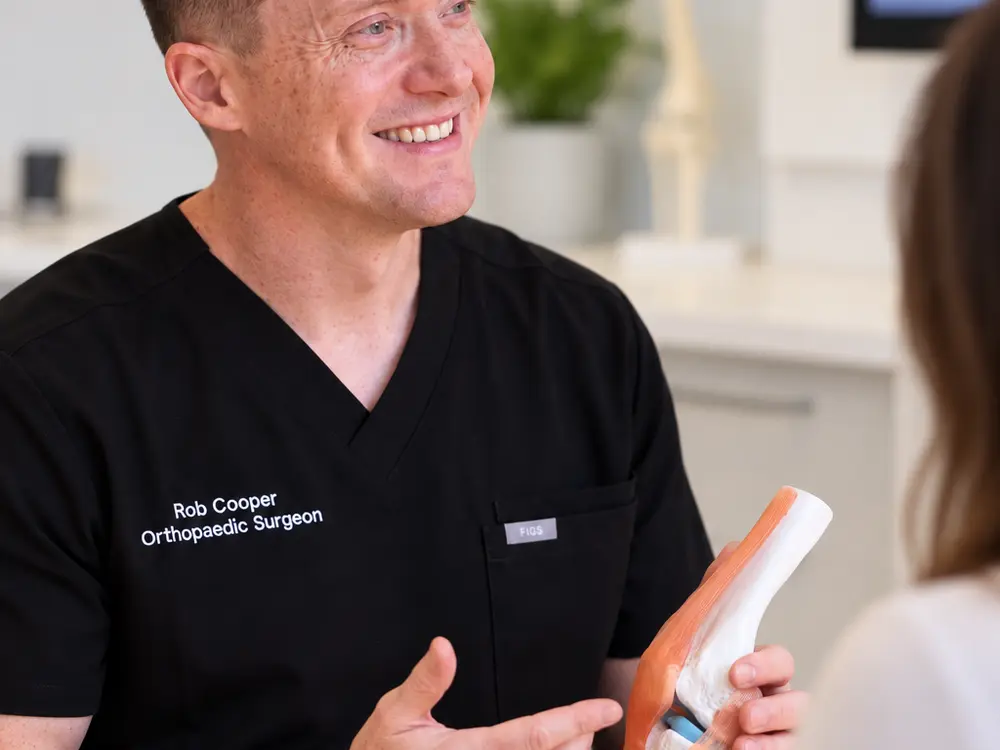 Dr Rob Cooper explaining a knee model to a patient in his consulting rooms