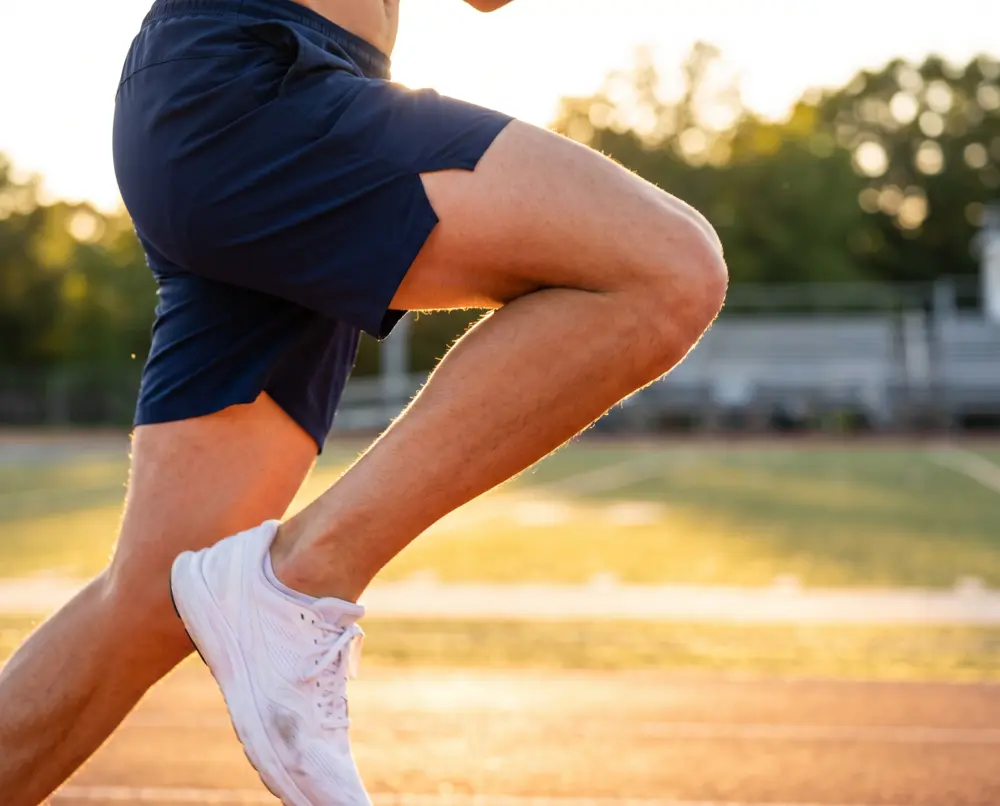 An athlete's knee driving forward mid-sprint at golden hour